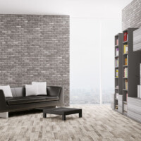 Interior of modern living room with grey brick walls, large long window in corner, dark grey couch and wooden ottoman on light wood flooring by Dralynn Floor Covering Inc.